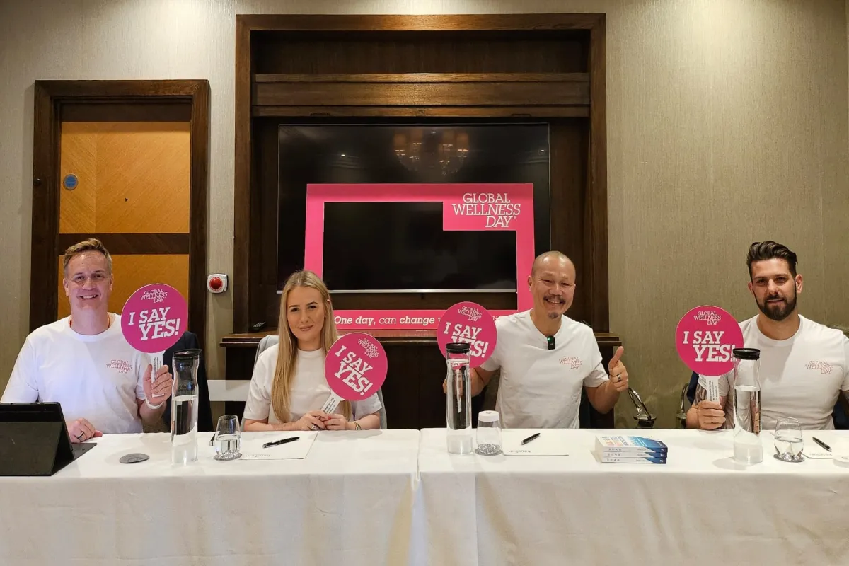 Frven on wellness panel at Jumeirah Global Wellness Day with fellow panelists holding 'I Say Yes!' signs