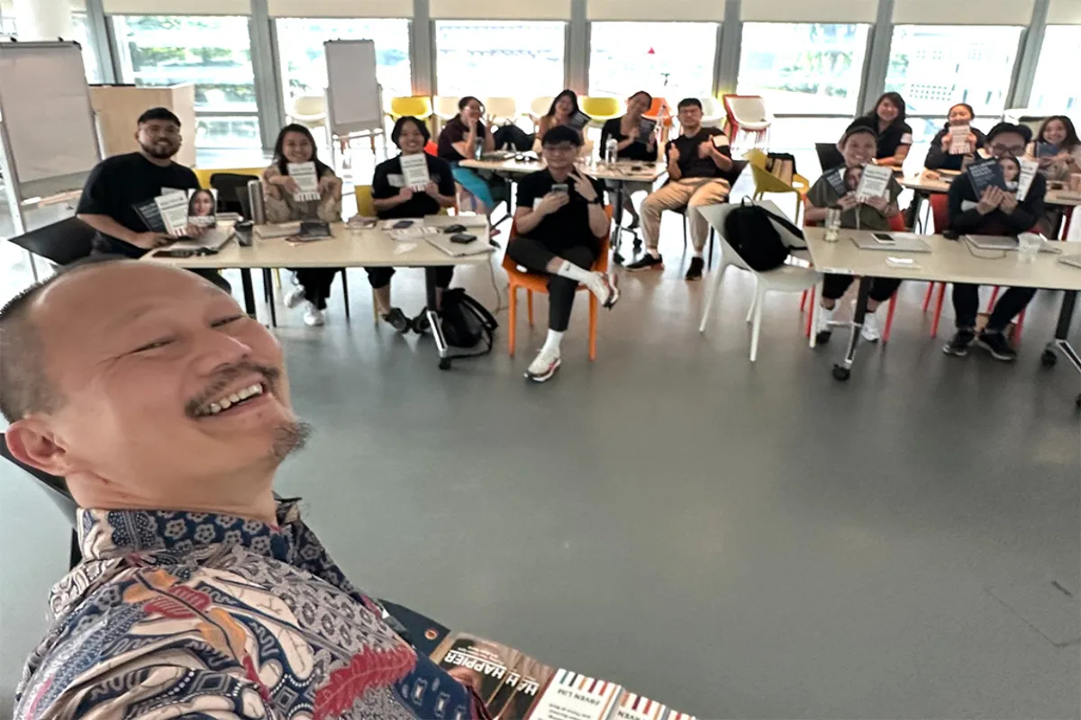 Frven taking selfie with workshop participants at URA - Team gathered around tables in bright conference room