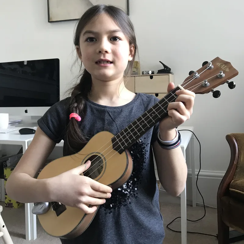 Older girl playing a ukulele at home
