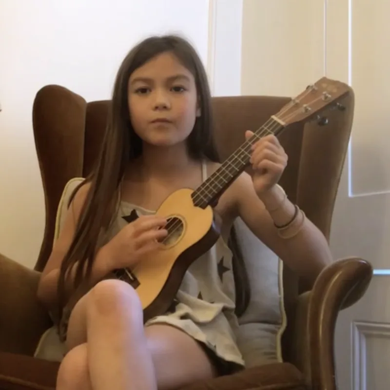 Girl practising ukulele in an armchair